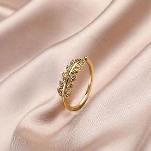 Elegant gold leaf ring with zircon stones on a champagne silk fabric background