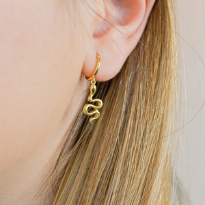 Close-up of a gold snake-shaped hoop earring worn by a model in a lifestyle setting