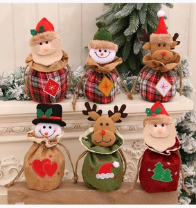 Détail de sachets cadeaux de Noël tricotés avec cordons, motifs Père Noël et élan festifs