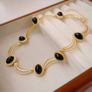 Macro detail of vintage gold chain necklace with oval black gemstones in a jewelry box