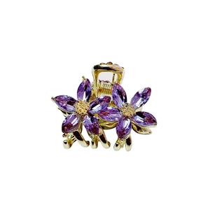 Golden metal hair claw clip with purple crystal flowers shown from a side view angle