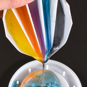 Close-up of 5-compartment silicone pouring cup with colorful liquid resin on black background