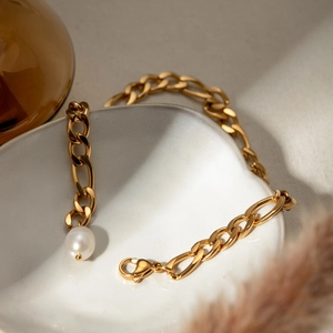 Detail of an 18K gold plated stainless steel Cuban chain anklet with a white pearl charm