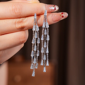 Detail of silver needle tassel earrings with shimmering crystals on an elegant model