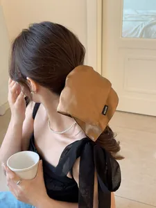 Detail of a brown satin hair scrunchie with Hand Made tag on a ponytail hairstyle