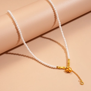 Détail d'un collier de perles avec pendentif gourde en or mat et accents de zircone