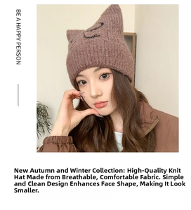 Nahaufnahme einer braunen Strickmütze mit Katzenohren und Stickerei an einem Model