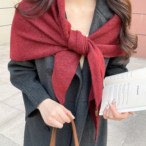 Détail d'un châle en tricot bordeaux avec texture et étiquette en cuir ronde de qualité