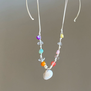Detail of handmade colorful beads and white shell pendant on a woven cord necklace