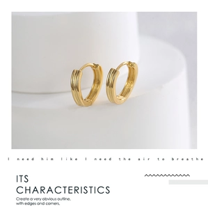Macro detail of gold-plated hoop earrings with textured ribbed design on white pedestal