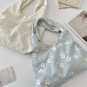Close-up of floral embroidery on off-white and light blue aesthetic tote bags