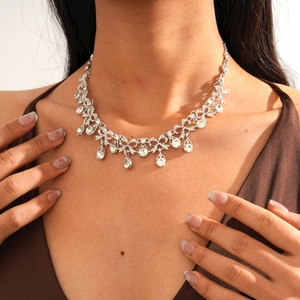 Close-up of sparkling water-drop pendant and bow necklace on model neck