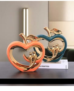 Detail of modern ceramic heart bird statues in vibrant orange and deep green finishes