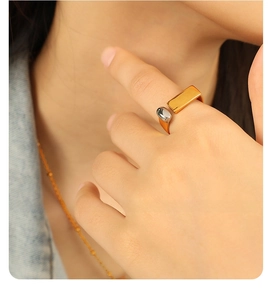 Close-up of minimalist gold and silver teardrop open ring worn on a finger