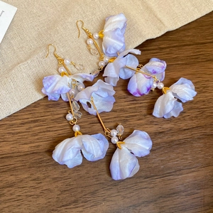 Vue détaillée de boucles d'oreilles fleurs en tissu violet avec perles sur fond bois