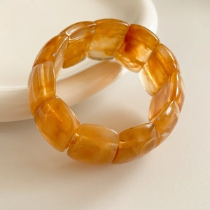 Macro shot of amber acrylic bracelet showing geometric resin beads with glossy texture