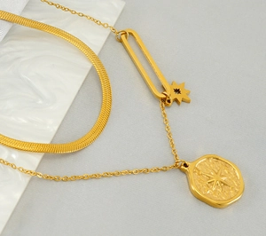 Detail of gold double-layered necklace featuring flat snake chain and starburst pendant