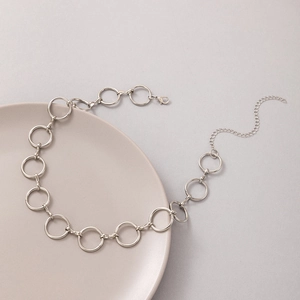 Collier chic à maillons ronds argentés avec fermoir mousqueton sur un plateau beige