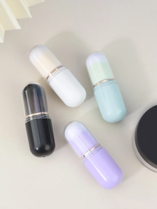 Close-up of four portable capsule makeup brushes in mint, white, black, and lilac colors