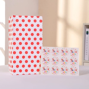 Detalle de bolsa de regalo de papel kraft blanco con lunares rojos y etiquetas de agradecimiento