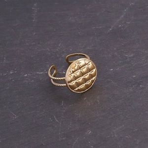 Detailed view of golden matelassé pattern ring with twisted band on stone texture