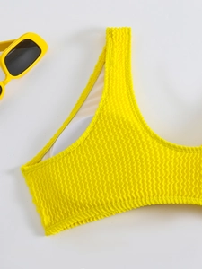 Detail of yellow pleated bikini top showing wavy texture and breathable white mesh lining