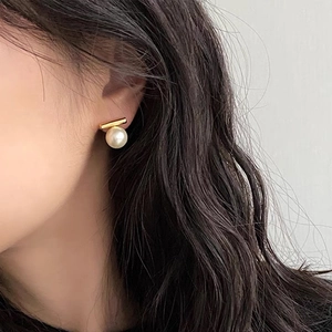 Nahaufnahme der minimalistischen Goldstab- und Perlenohrringe an einem Model