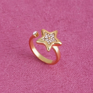 Gros plan détaillé d'une bague étoile dorée avec strass sur un fond de velours rose