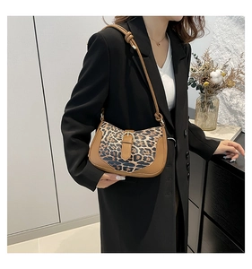 Detail of trendy leopard print underarm bag with decorative metal buckle on model