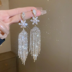 Macro view of long silver tassel earrings with flower studs and sparkling zirconia