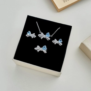 Close-up of S925 silver jewelry set with blue heart stones and bow design in a gift box