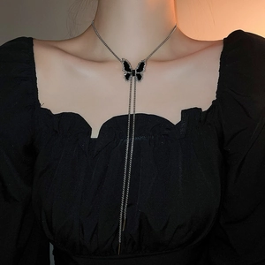 Detail of Y-shaped necklace featuring a black butterfly pendant with sparkling tassels