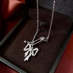 Sparkling zircon bow and safety pin pendant necklace on elegant black velvet background