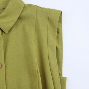 Close-up of mustard green linen dress showing woven texture, lapel, and matching button