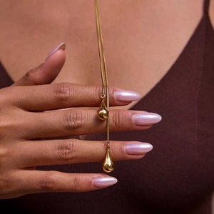 Détail des pendentifs en forme de goutte d'or poli sur un collier en Y minimaliste