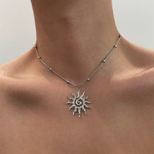 Detail of silver hollow sun pendant with spiral texture on beaded snake chain necklace