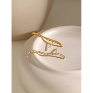 Detail of wavy gold earrings with white rhinestones leaning on white ceramic vessel
