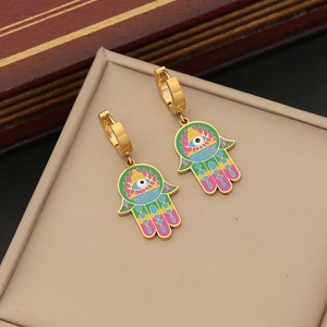 Gold Hamsa Hand huggie earrings with colorful enamel and eye motif on a display