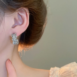 Gros plan d'une boucle d'oreille en C argentée avec texture scintillante sur modèle