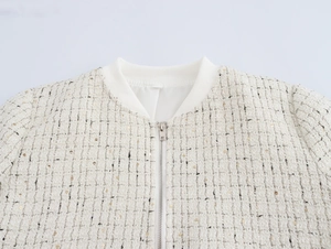 Détail de la texture en tweed et du zip argenté sur la veste blanc crème à paillettes