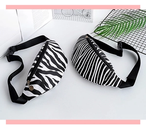 Close-up of zebra pattern canvas waist bags with adjustable straps and metal charms