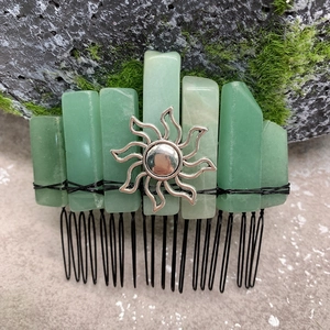 Detail of green crystal hair comb with silver sun charm on a natural mossy rock