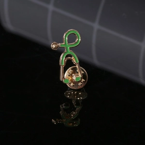 Macro detail of a green enamel stethoscope brooch with golden base and butterfly clasp