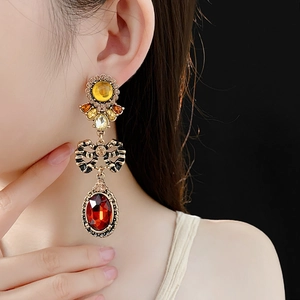 Detail view of vintage long earrings with multicolor gemstones on a model against black background