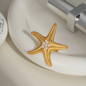 Golden starfish ring with white pearls on a ceramic tray in a minimalist scene