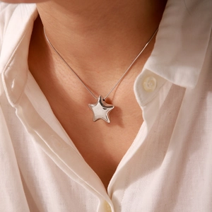 Macro shot of silver star-shaped pendant on a fine snake chain necklace for women