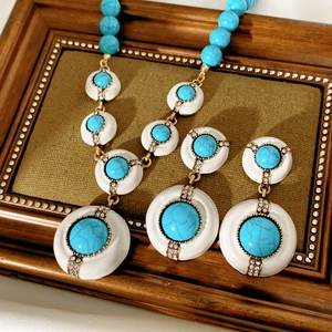 Detailed view of vintage gold necklace and earring set with turquoise and white resin