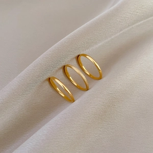 Three-piece minimalist gold titanium steel rings with matte and polished finishes on silk