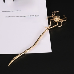 Macro detail of gothic gold metal hair pin featuring a spider on a skull and bone stick