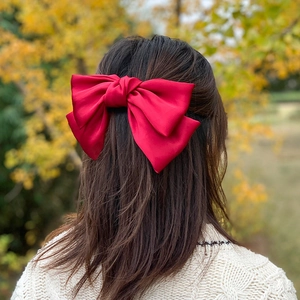 Rear view of a large red satin bow hair clip worn in a classic updo hairstyle